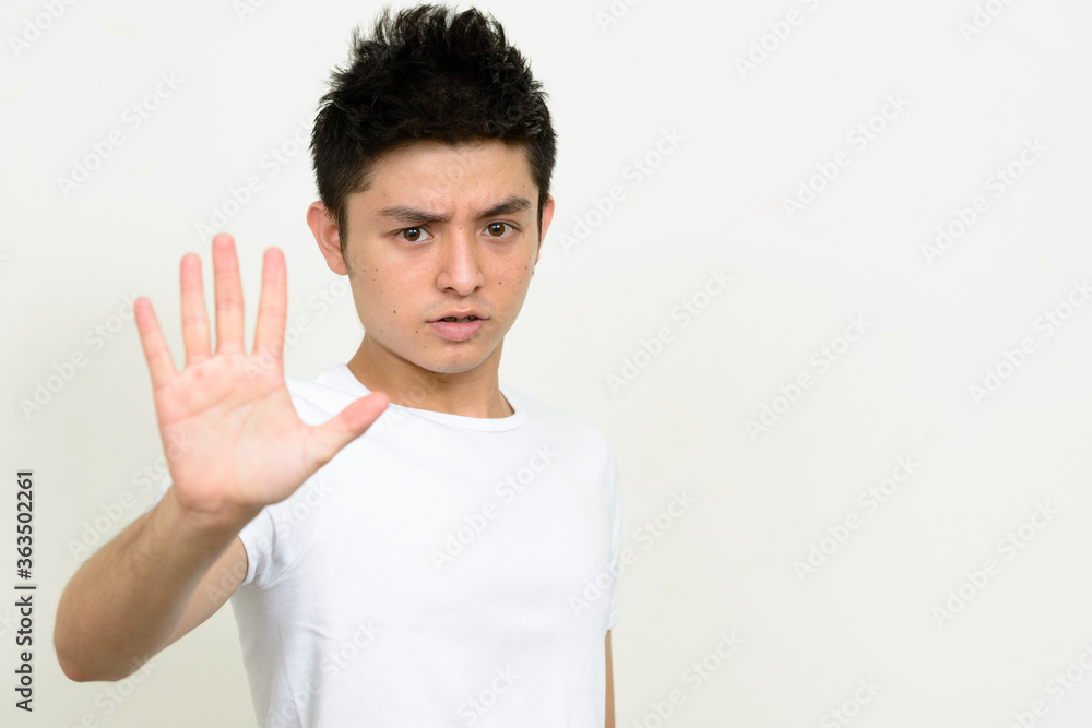 Portrait of stressed young Asian man showing stop gesture Portrait of stressed young Asian man showing stop gesture