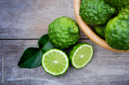 Fresh green Bergamot or kaffir lime fruit with slice isolated onrustic wood table background . Herbal medicine plant concept. photo