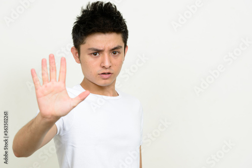 Portrait of stressed young Asian man showing stop gesture