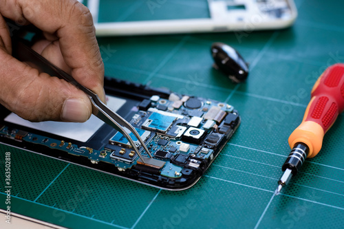 Εκτύπωση καμβά Technician man hand repairing and  assembling the motherboard of mobile smart phone by using soldering and forceps in lab room