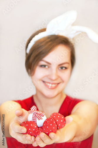 Young woman wearing easter bunny ears. She is holding easter eggs.