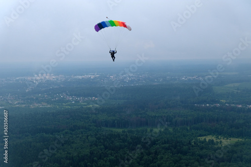 Skydiving. A rainbow colored parachute flies in the sky