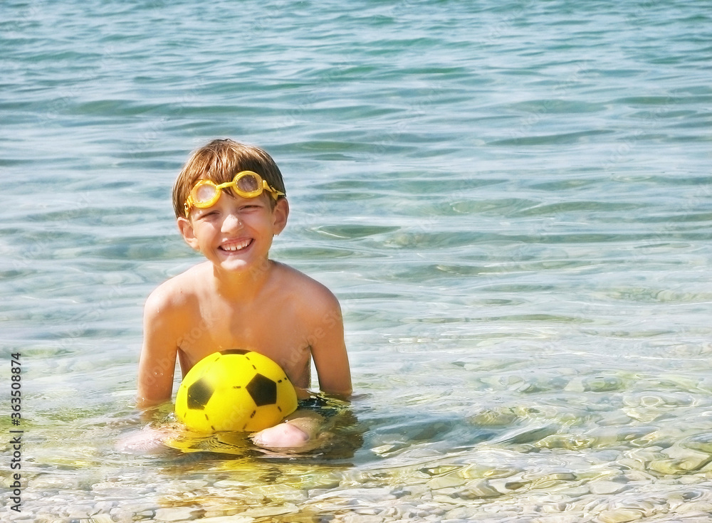 Child (boy) with ball at the sea. Beach.