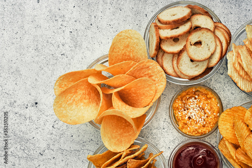 Canvas Print Potato and corn chips, snacks, crackers in transparent glass plates and sauces