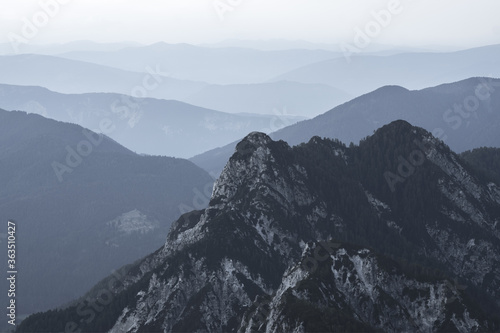 Canvas Print Spectacular view of grey mountain ranges silhouettes and fog in valleys