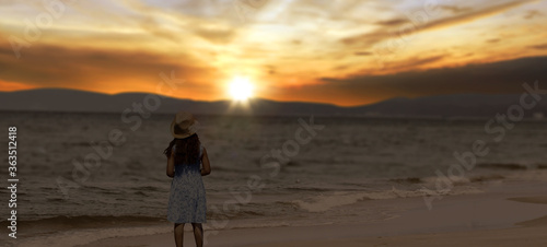 little girl stands on the beach at sunset.
