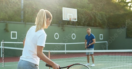Happy young couple playing tennis on tennis court.