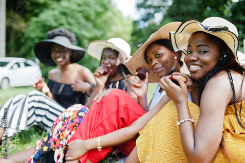 Group of african american girls celebrating birthday party and eat muffins outdoor with decor.