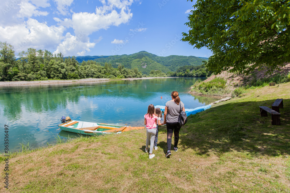 Family enjoy nature on summer day by river, beautiful nature , wooden boats on the water Family enjoy nature on summer day by river, beautiful nature , wooden boats on the water