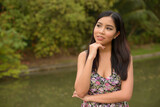 Portrait of happy young beautiful Asian woman thinking at the park