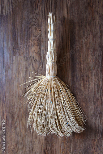 Billede på lærred Old straw besom on a wooden background
