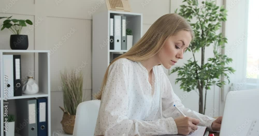 Businesswoman writing notes in book at office Businesswoman writing notes in book at office