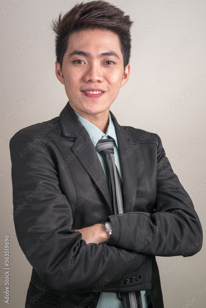 Portrait of happy young Asian businessman in suit with arms crossed Portrait of happy young Asian businessman in suit with arms crossed