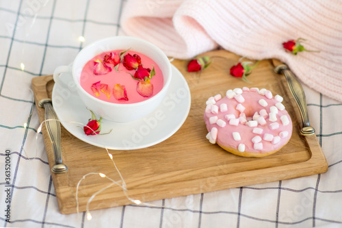 pink breakfast in bed, donut and moonlit pink milk with pink flowers, wooden tray on a white bed, romantic breakfast