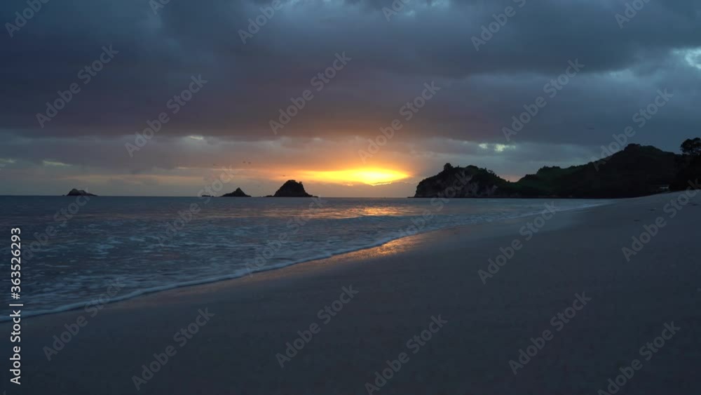 Sunrise at Hahei beach with islets on the horizon Sunrise at Hahei beach with islets on the horizon