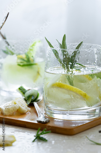 Refreshing iced drink with lemon and fresh rosemary, detox summertime