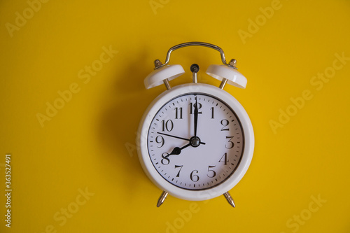 Vintage alarm clock with old white bells, with yellow background. Concept of a retro watch. Copy space