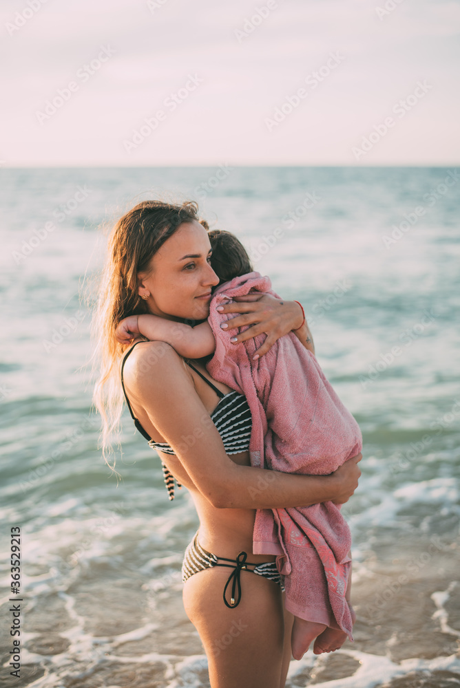 Mother with her daughter in her arms against the background of the sea of Azov in Crimea Mother with her daughter in her arms against the background of the sea of Azov in Crimea