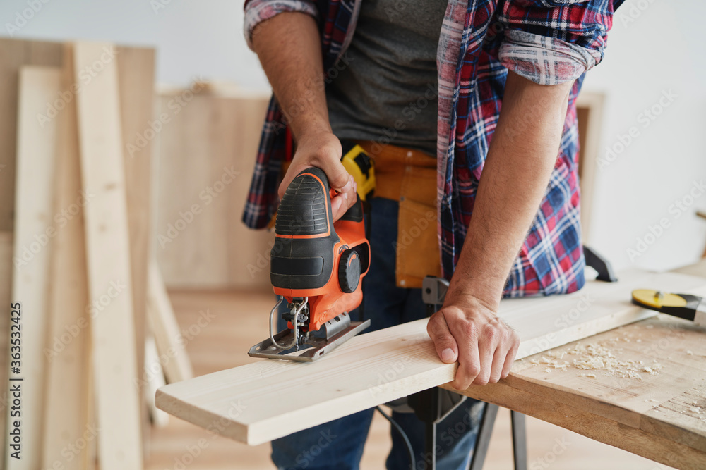 Unrecognizable person sawing wood with an electric jigsaw