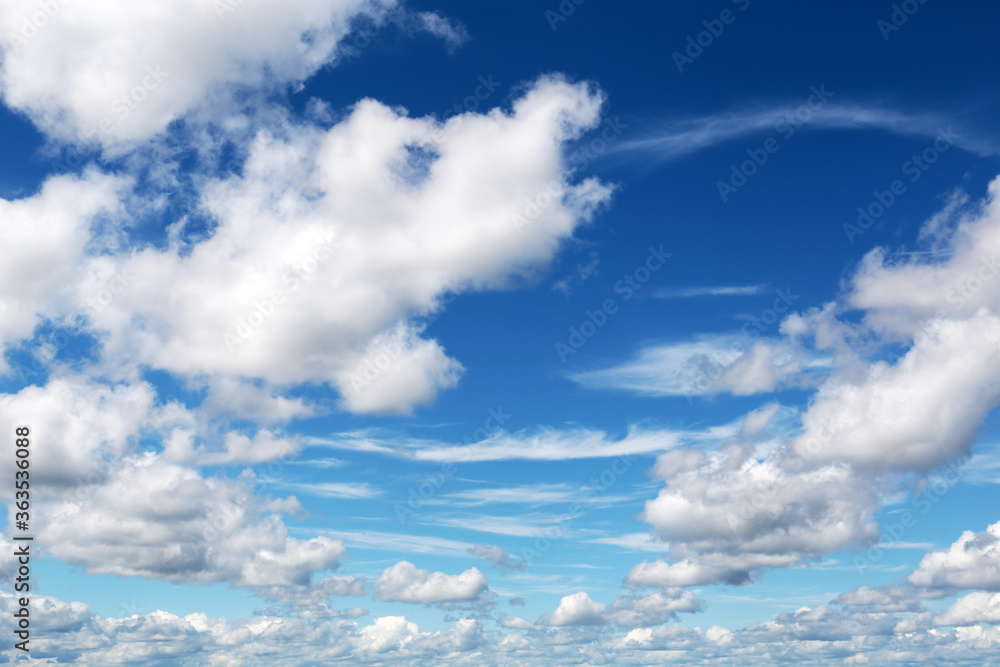 Blue sky covered with white cumulus and cirrus clouds. Summer cloudscape, beautiful weather background Blue sky covered with white cumulus and cirrus clouds. Summer cloudscape, beautiful weather background