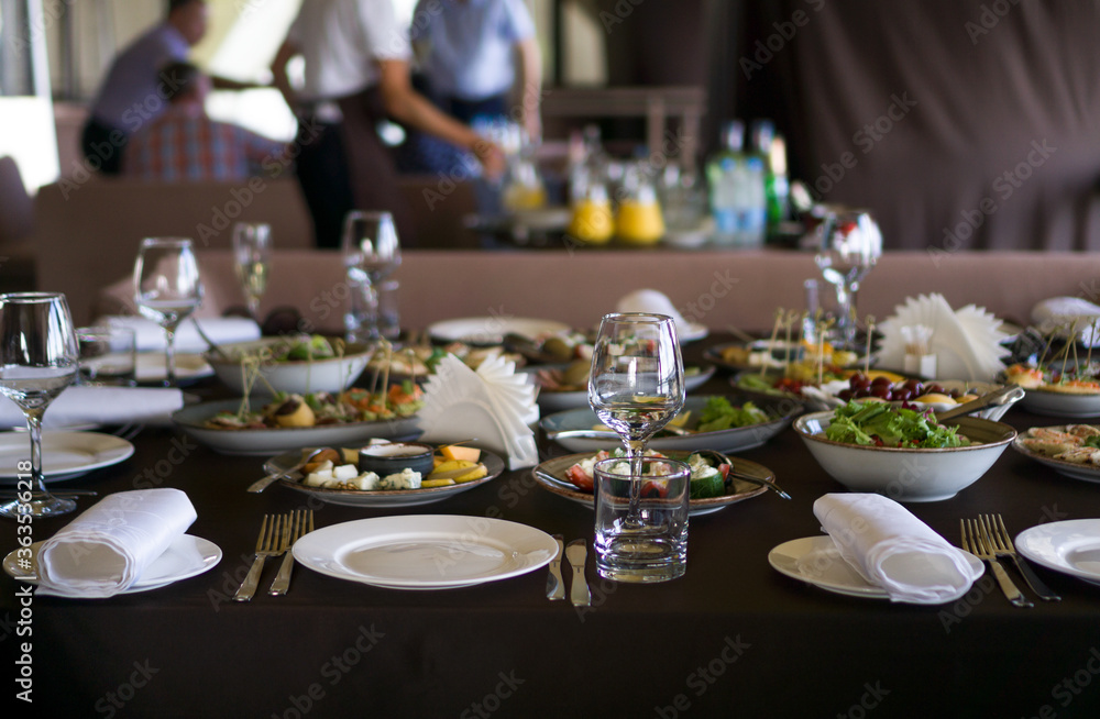 Fototapeta premium Served for a banquet table. Wine glasses with napkins, glasses and salads.
