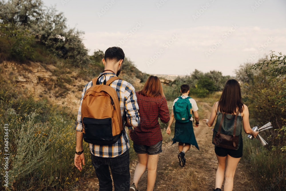 Group of four of tourists hiking in mountains, in a forest.