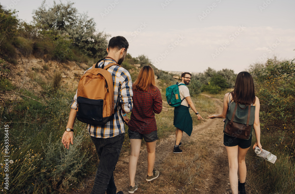 Group of four of tourists with backpacks hiking in mountains, in a forest. Concept of domestic tourism.