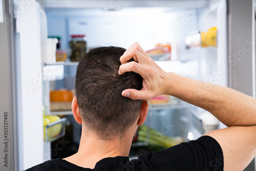 Hungry Confused Man Looking In Open Fridge