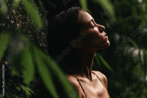 portrait of young beautiful woman on green leafs back