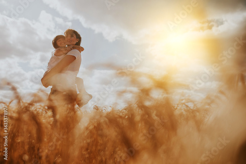 mother and daughter hugging in a wheat field under a sunset