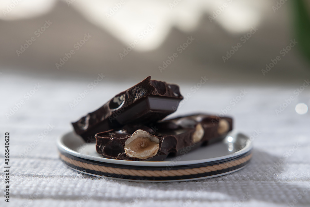 cup of tea or coffee and a pair of seductive pieces of dark chocolate with hazelnuts on the table cup of tea or coffee and a pair of seductive pieces of dark chocolate with hazelnuts on the table