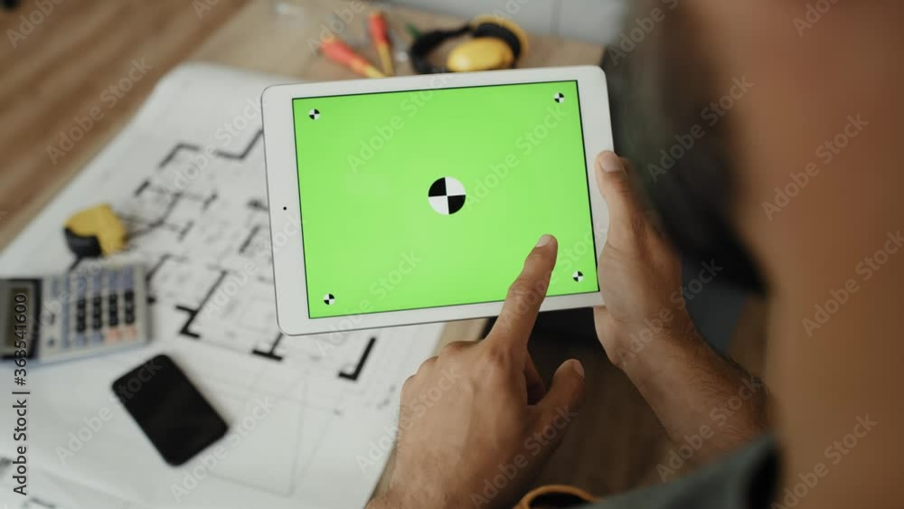 Handheld video of carpenter looking at something on a tablet. Shot with RED helium camera in 8K Handheld video of carpenter looking at something on a tablet. Shot with RED helium camera in 8K