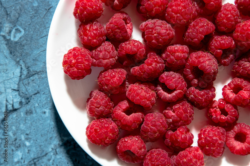 a lot of sweet fresh red raspberries on a plate from the market or garden