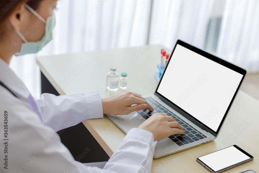 Female doctors in uniform are using laptops and smartphone for medical work at modern hospital. empty monitor for your design. Laptop and smartphone mockup. Female doctors in uniform are using laptops and smartphone for medical work at modern hospital. empty monitor for your design. Laptop and smartphone mockup.