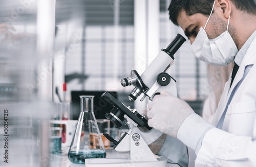 Billede på lærred Male scientist working looking at Microscope with sample test tube in a chemistr