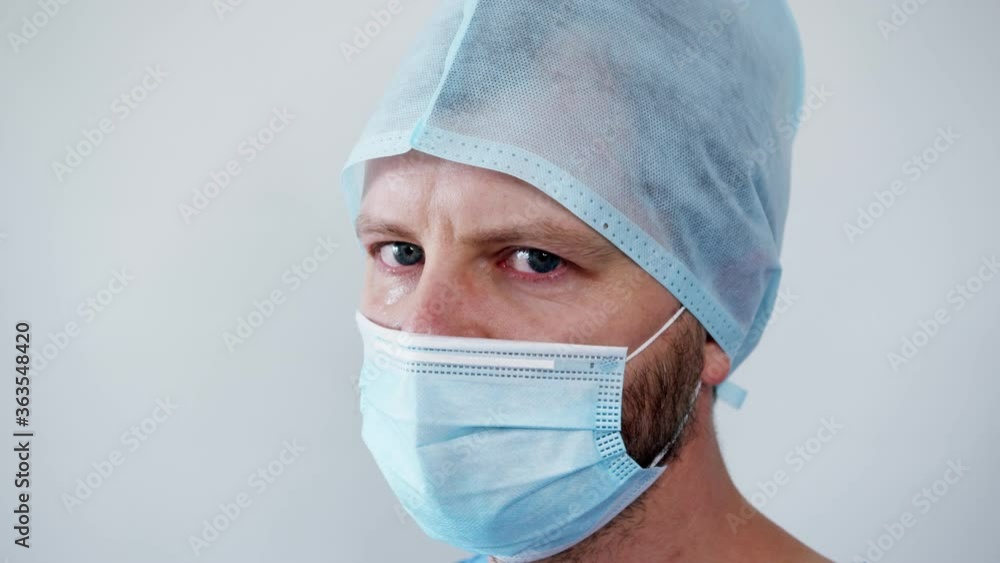 the upset doctor in the bandage looks straight into the camera with a piercing look. fatigue and despair of medics during the pandemic covid-19 coronavirus . High quality footage the upset doctor in the bandage looks straight into the camera with a piercing look. fatigue and despair of medics during the pandemic covid-19 coronavirus . High quality footage