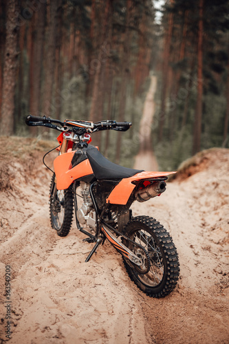 Orange motocross bike on sand in forest