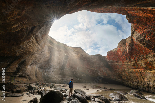 hiker in the ocean cave of Devil's Punch Bowl on the Oregon coast