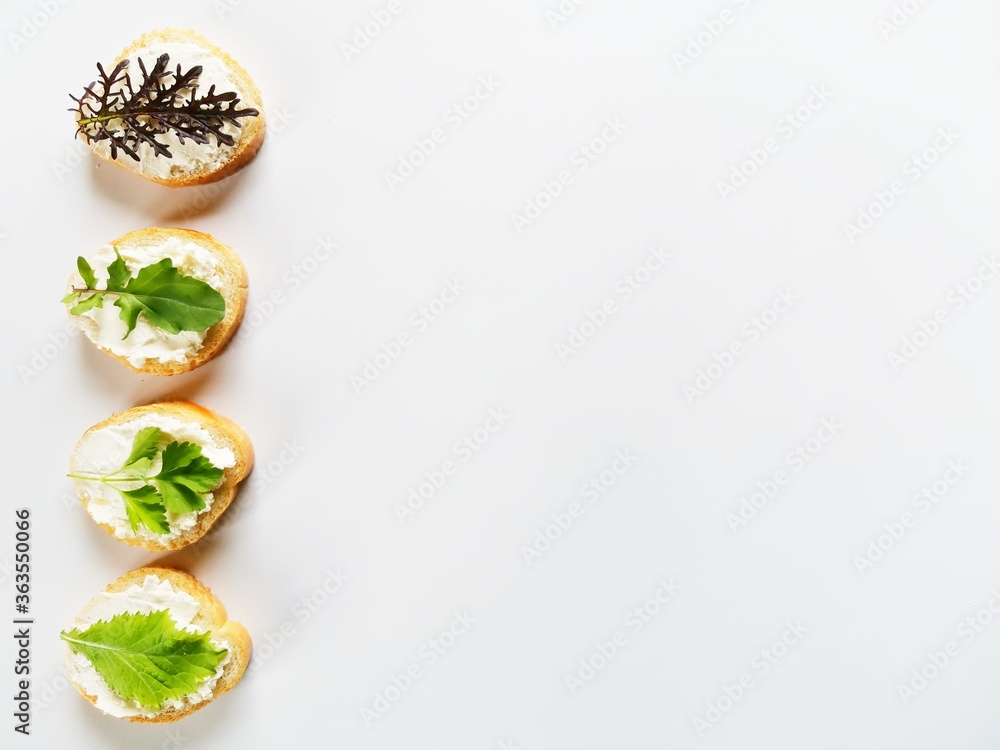 4 delicious sandwiches with fresh mustard, parsley, arugula and soft cheese on a white background