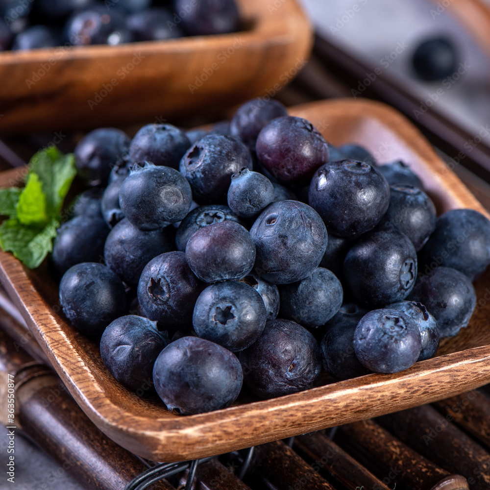 Pile of blueberry fruit in a bowl plate on a tray over gray cement concrete background, close up, healthy eating design concept. Pile of blueberry fruit in a bowl plate on a tray over gray cement concrete background, close up, healthy eating design concept.