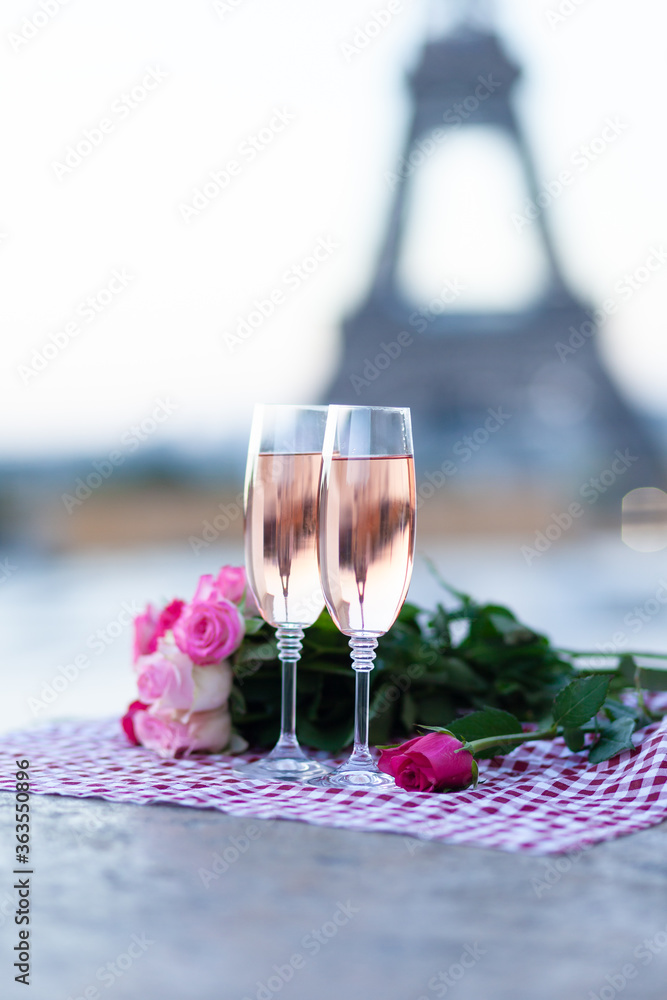 Beautiful and romantic proposal on Saint Valentine's day in Paris - city of love. Bouquet of pink roses, two glasses of wine, raspberry. Eiffel tower on background. Close up copy space. Tonned Beautiful and romantic proposal on Saint Valentine's day in Paris - city of love. Bouquet of pink roses, two glasses of wine, raspberry. Eiffel tower on background. Close up copy space. Tonned