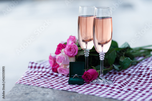 Beautiful and romantic proposal on Saint Valentine's day in Paris - city of love. Bouquet of pink roses, two glasses of wine, diamind ring in the box. Eiffel tower on background. Close up copy space photo