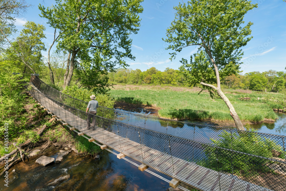 Fototapeta premium a hiker crossing a suspension bridge