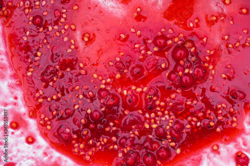 Amaranth surface of squeezed currant. Currant juice, yellow seeds, whole berries in a bowl. Copy space. 