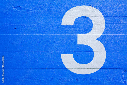 Blue concrete wall with stencil number 3