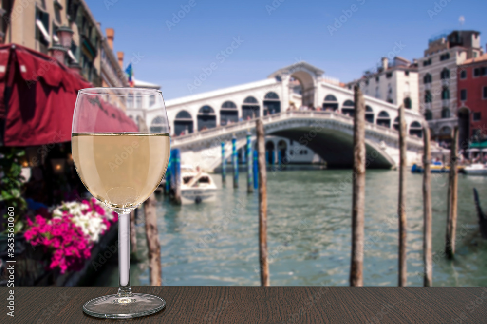 Glass of white wine with view on  famous Canal Grande and Rialto Bridge in Venice, Italy