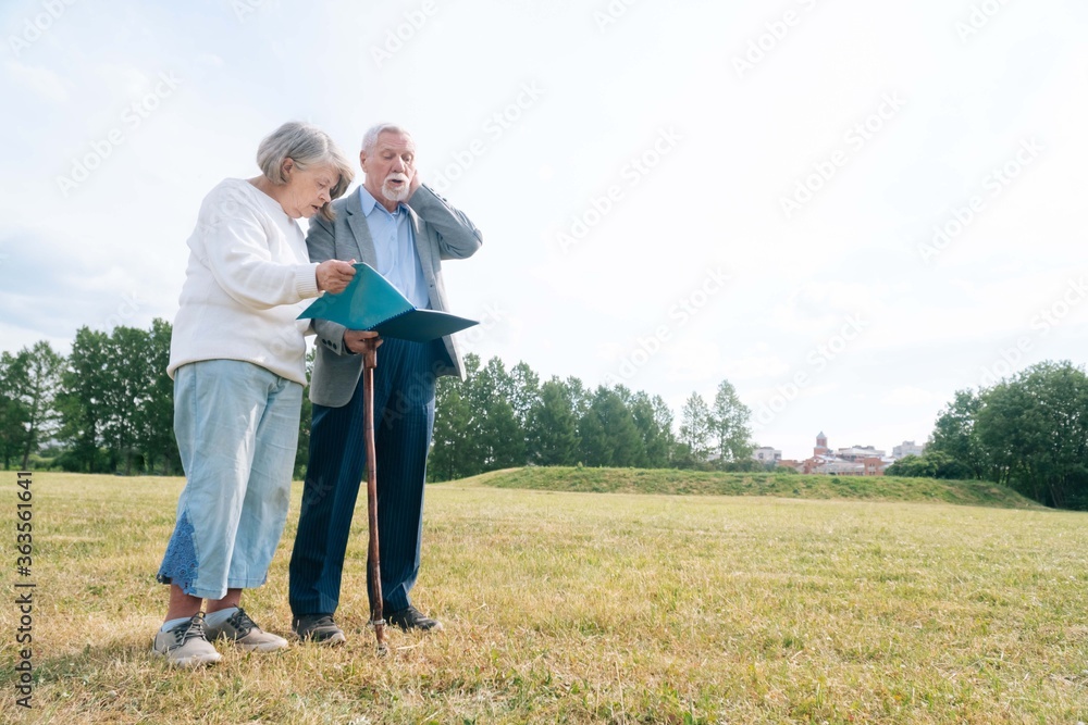 Portrait of a gray haired senior Caucasian people holding a folder with documents on the background of nature Portrait of a gray haired senior Caucasian people holding a folder with documents on the background of nature