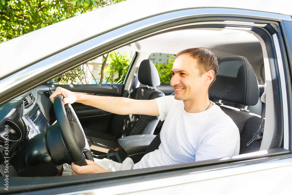 Riding his new car. Side view of handsome young man driving his car and smiling Riding his new car. Side view of handsome young man driving his car and smiling