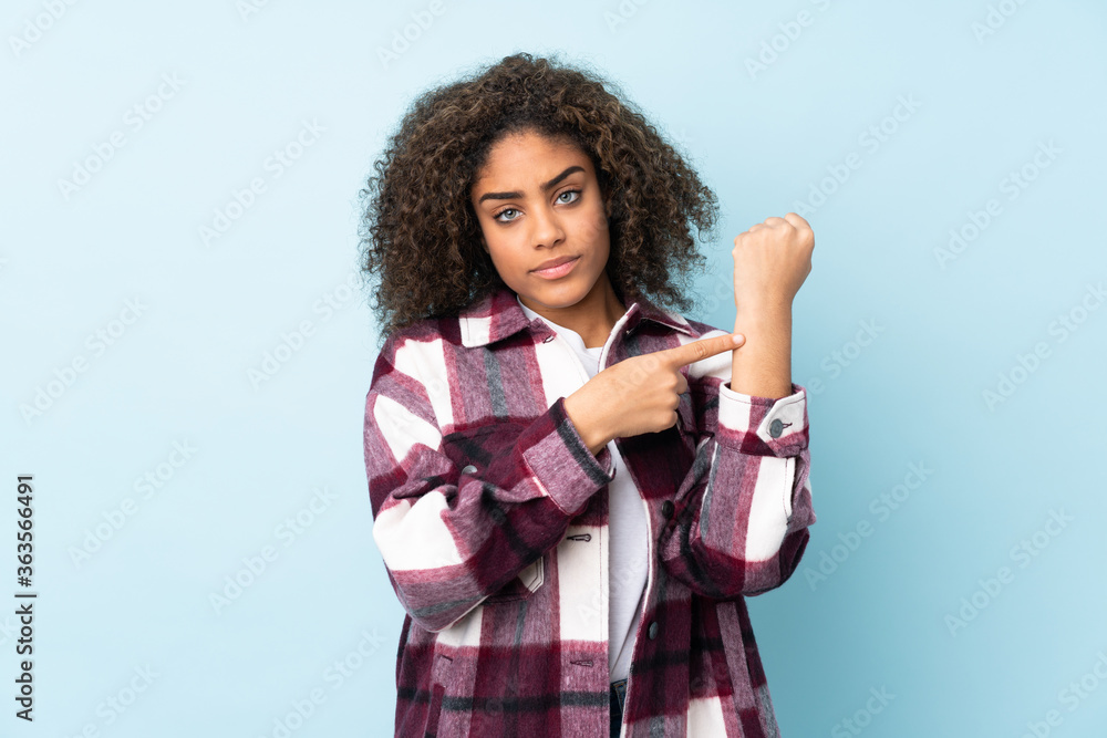 Young African American woman isolated on blue background making the gesture of being late Young African American woman isolated on blue background making the gesture of being late