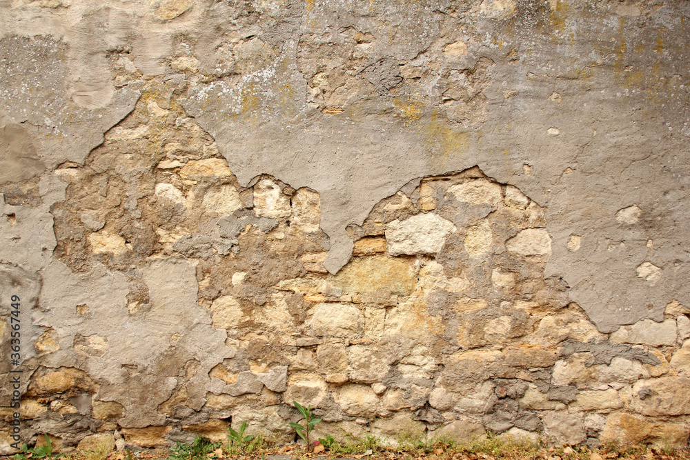 horizontal texture of an old wall made of rubble stone, brown sandstone, with the remains of cracked old plaster, a blank for the designer, wallpaper